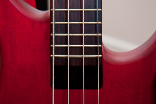  Bass guitar strings and frets on a beautiful red instrument