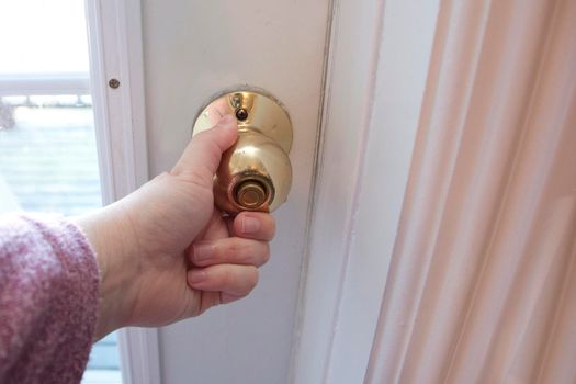  hand on a gold door handle shutting or opening a door 