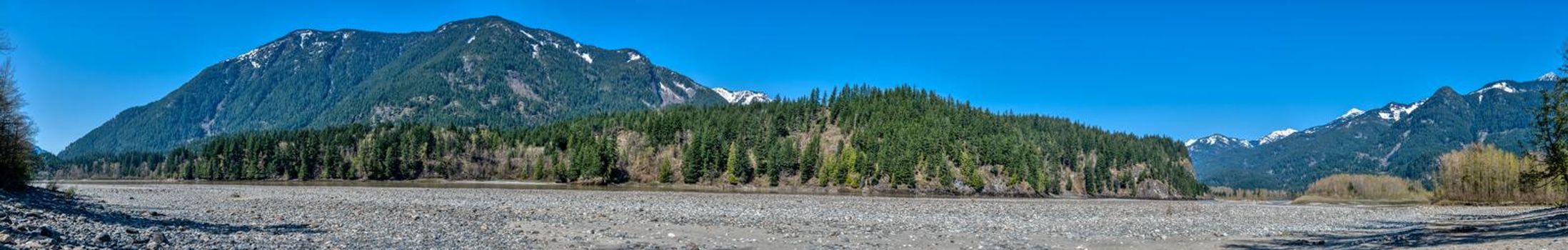 Panoramic view of Rocky mountains in British Columbia. Stoney riverbed in the mountains