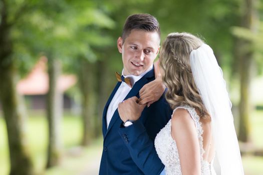 Bride and groom hugging tenderly posing during photo shooting in park. Caucasian happy romantic young couple celebrating their marriage.