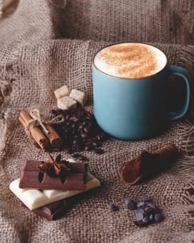 cup of coffee, chocolate, beans, anise and cinnamon on wooden background