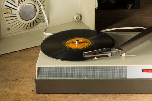 Old plastic record player playing a vinyl with a yellow label.