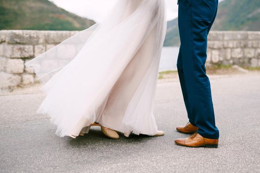 Groom and bride stand against the background of the stone wall. High quality photo