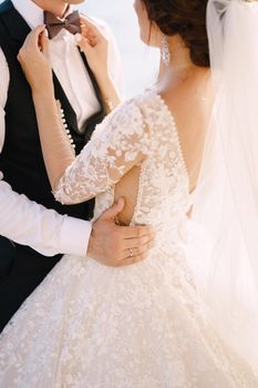 Close-up of the bride's hands. Plays with his fingers with the groom's bow tie.