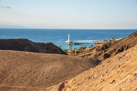 Eilat, Israel - March 31 2021: Mountains in the desert against the backdrop of the Red Sea with the Eilat Underwater Observatory Marine Park. Shlomo mountain, Eilat Israel, Mars like Landscape