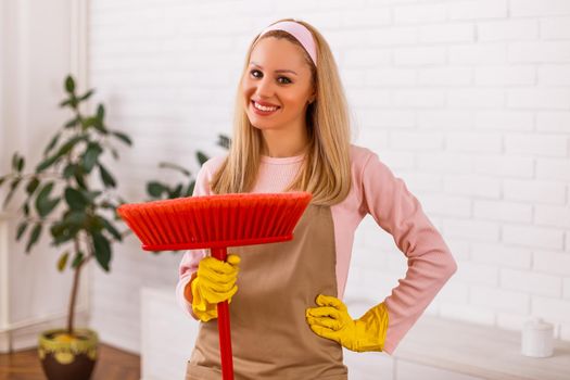 Beautiful housewife cleaning with broom her home.