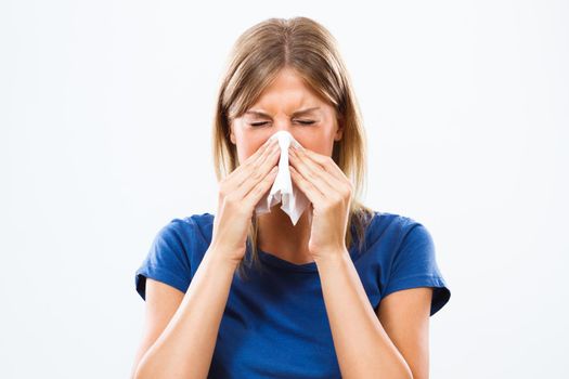 Young woman is having flu and she is blowing her nose