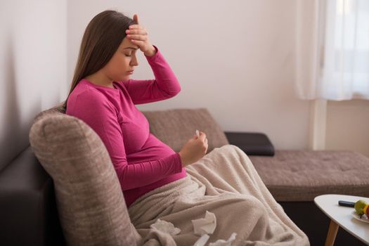 Exhausted pregnant woman having flu and checking temperature.