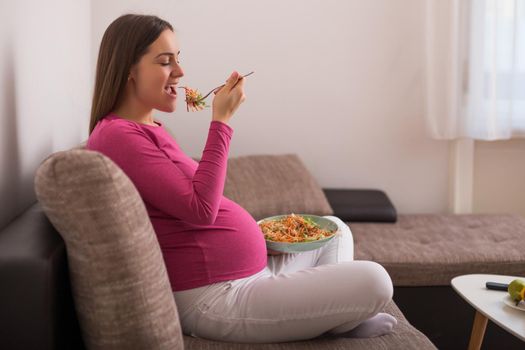 Happy pregnant woman eating salad.