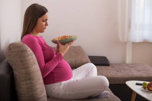 Sad pregnant woman doesn't want to eat vegetables.