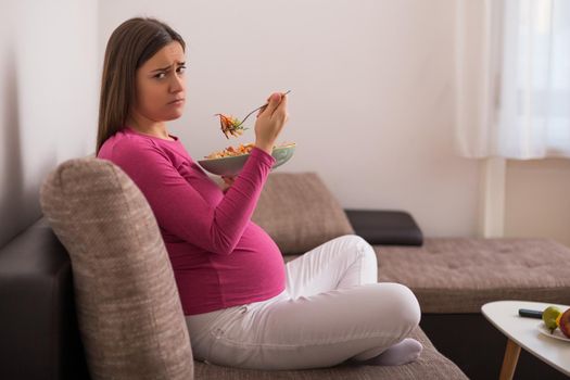 Sad pregnant woman doesn't want to eat vegetables.