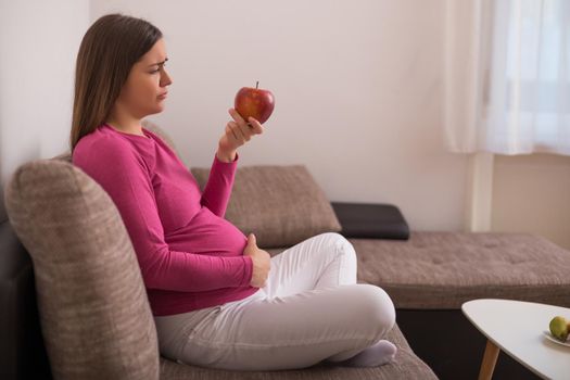 Sad pregnant woman doesn't want to eat fruit.