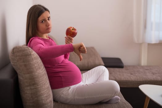 Sad pregnant woman doesn't want to eat fruit.