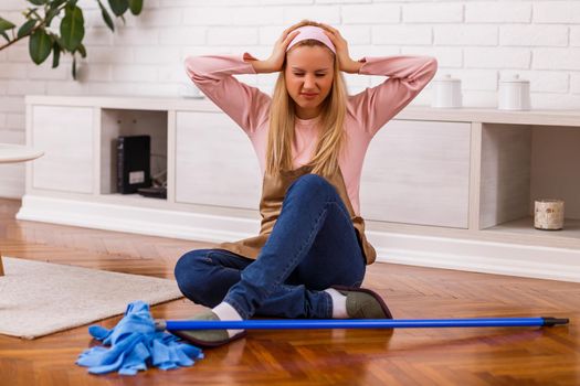 Image of  overworked housewife with mop sitting in the living room.