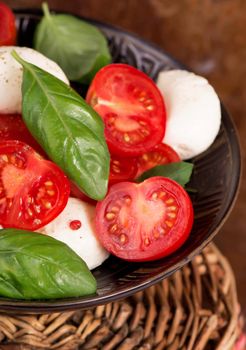 Round camembert cheese with cherry tomatoes and basil .