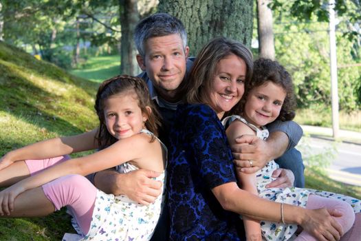 father, mother and their two beautiful daughters in a portrait outside