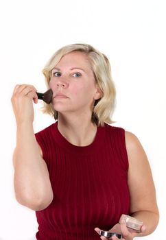 woman with red face puts on makeup powder from a case in the studio 