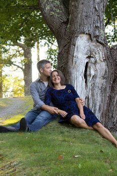 man holds giggling woman who looks at something in the distance at the park 