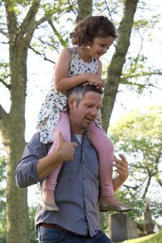 little girl rides on the shoulder of her father 