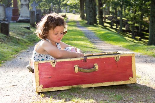 a small lonely girl in a red box in a cemetery 