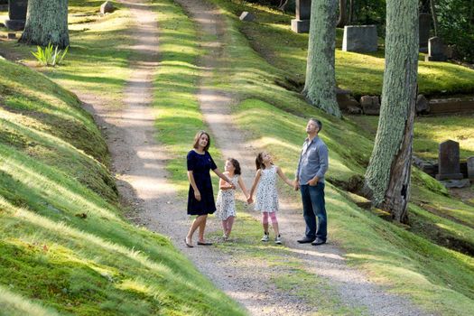 parents holding hands with two daughters walking and exploring on a path looking around