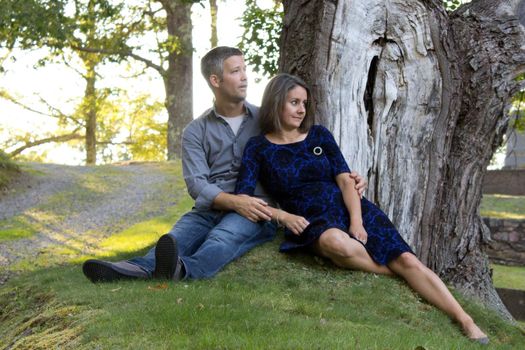 beautiful woman and handsome man relax outside under a big tree in summer