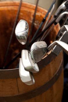 Collection of golf clubs, irons and drivers are in a container at a clubhouse waiting to be used