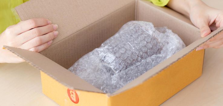 Closeup hand of woman opening parcel box with check product at home, female unpack with knife, delivery and shipping, shipment and express for shop, online shopping store and service concept.