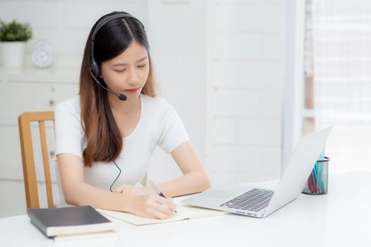 Young asian woman wearing headphone study online with e-learning on desk, girl wearing headset learning to internet with laptop computer at home, new normal, distance education and training.