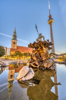 The Neptune Fountain at Alexanderplatz in Berlin at sunrise with the famous Fernsehturm and the Marienkirche