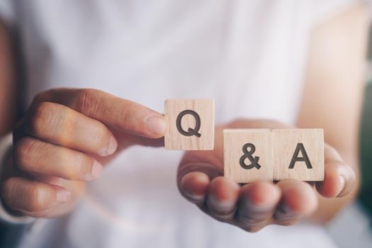 Q and A alphabet on wooden cube in hand hold with background. Question and answer meaning concept.