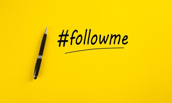 Word follow me or hashtag followme hand written with a black marker pen on yellow background.