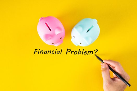 A hand writes the words FINANCIAL PROBLEM on the yellow background. Business and finance concept