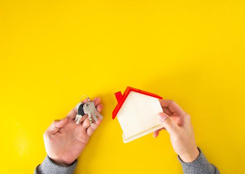 The house and key on the  hands on yellow background