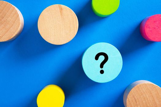 Question mark icon on blue wooden block on blue background. Mystery, uncertainty or problem solving concept.
