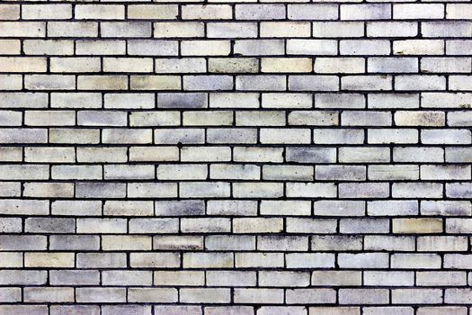 Photograph of a brick wall pattern. The bricks are red, blue, pink and purple in colour with white mortar.