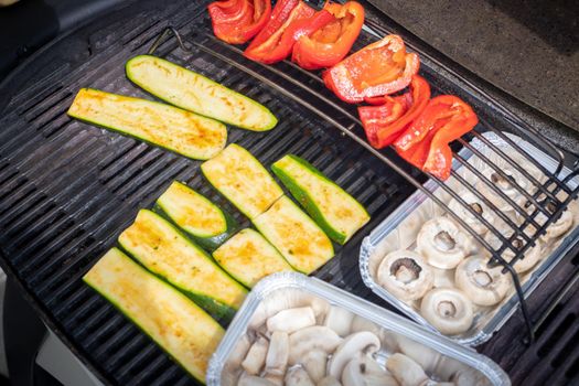 Close up of cheese and vegetables on gas grill. Summer time, outdoors.
