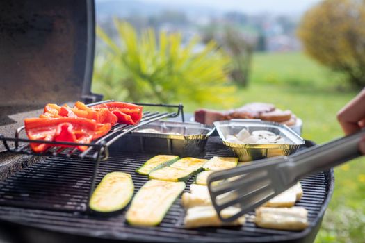 Close up of cheese and vegetables on gas grill. Summer time, outdoors.