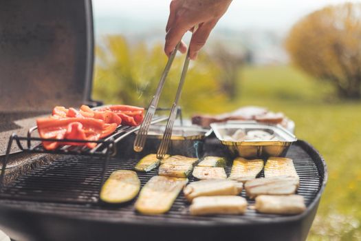 Close up of cheese and vegetables on gas grill. Summer time, outdoors.