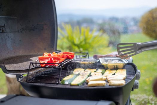 Close up of cheese and vegetables on gas grill. Summer time, outdoors.