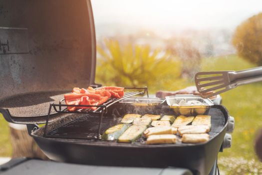 Close up of cheese and vegetables on gas grill. Summer time, outdoors.