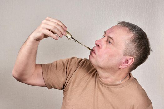 A man pulls out a smelt fish gnawed to the bone with his hand. Close up