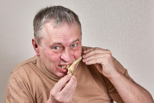 Man eating fried smelt fish holding fish with hands in front of face. Close up