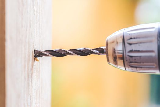 Do it yourself home handyman is using a drill for drilling wood