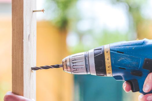 Do it yourself home handyman is using a drill for drilling wood