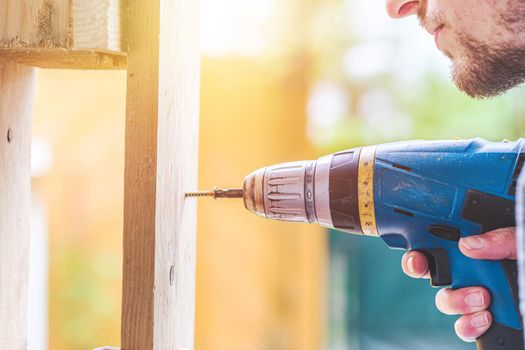 Do it yourself home handyman is using a cordless screwdriver for screwing