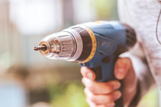 Do it yourself home handyman is holding a cordless screwdriver, outdoors