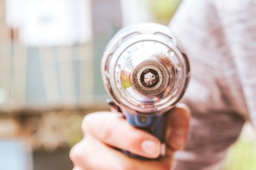 Do it yourself home handyman is holding a cordless screwdriver, outdoors