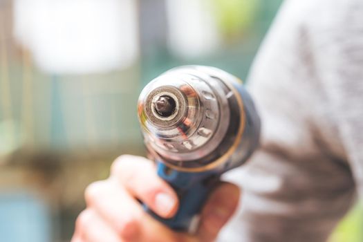 Do it yourself home handyman is holding a cordless screwdriver, outdoors
