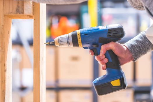 Do it yourself home handyman is using a cordless screwdriver for screwing